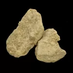 Cluster of rough, light‑beige rocks with a granular surface against a black background.