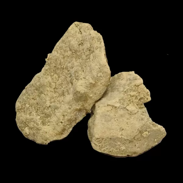 Cluster of rough, light‑beige rocks with a granular surface against a black background.