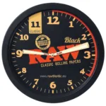 Round wall clock with RAW branding and orange numerals on a black face; beige hands and promotional text.