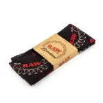 Raw rolling papers pack wrapped in black paper with red RAW logos and a beige paper band on a white background